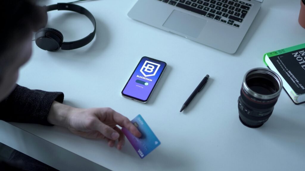 Person holding credit card by digital currency app, exploring blockchain technology.